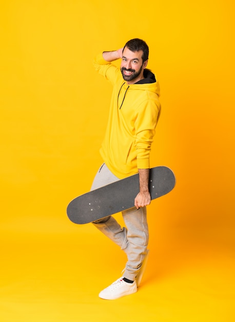 Full-length shot of a skater man over isolated yellow 