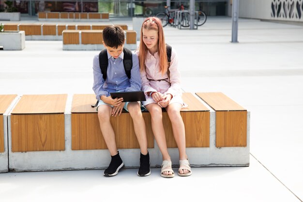 Full length shot of two young teen siblings using a digital tablet near school, doing homework