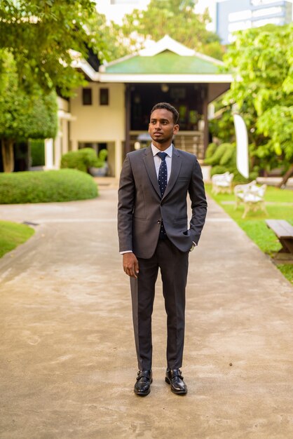 Full length shot of young handsome African businessman standing outdoors