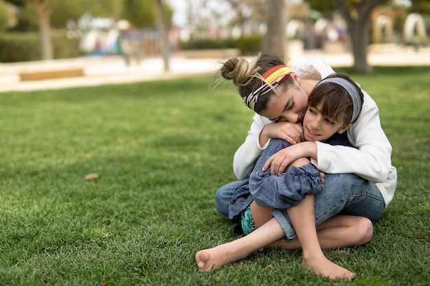 Full length of siblings embracing on field at park