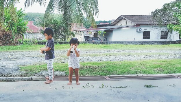 Photo full length of siblings playing in back yard