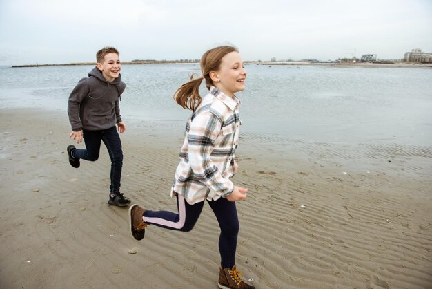 Photo full length of siblings running on beach