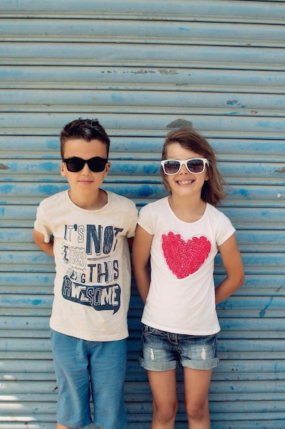 Photo full length of siblings wearing sunglasses against shutter