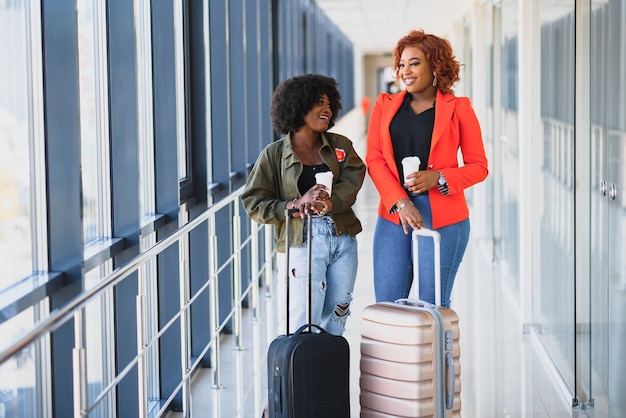 Full length side portrait of young black woman walking with suitcase in airport