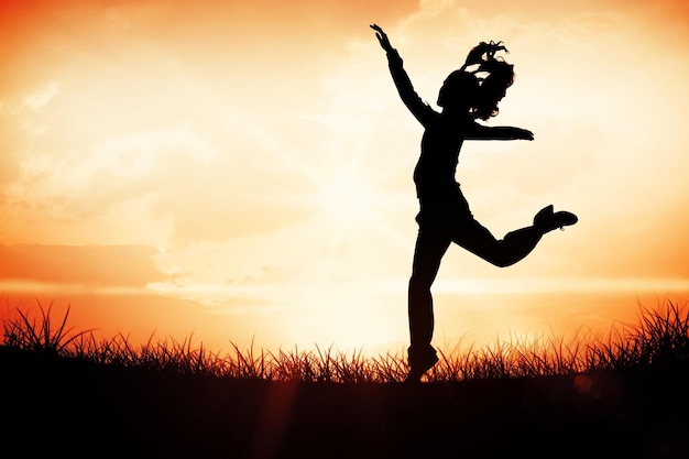 Full length side view of a sporty young blond jumping against orange sunrise