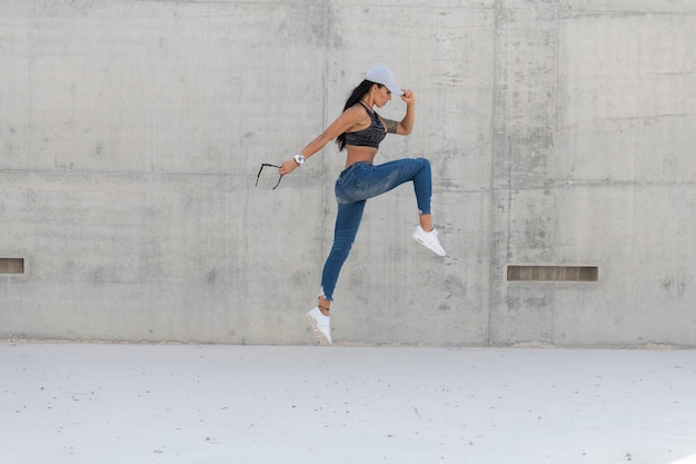 Photo full length side view of woman jumping against wall