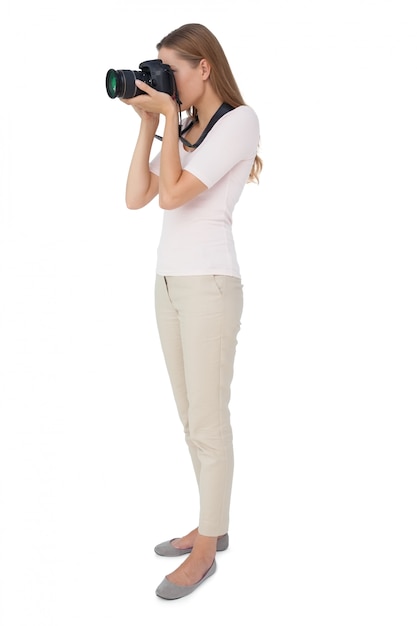 Full length side view of a woman with camera over white background