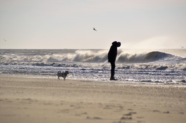 Photo full length of silhouette man standing on beach against clear sky