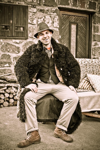 Photo full length of smiling man sitting against building