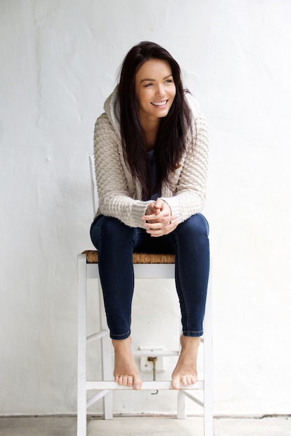 Full length smiling young woman sitting on chair