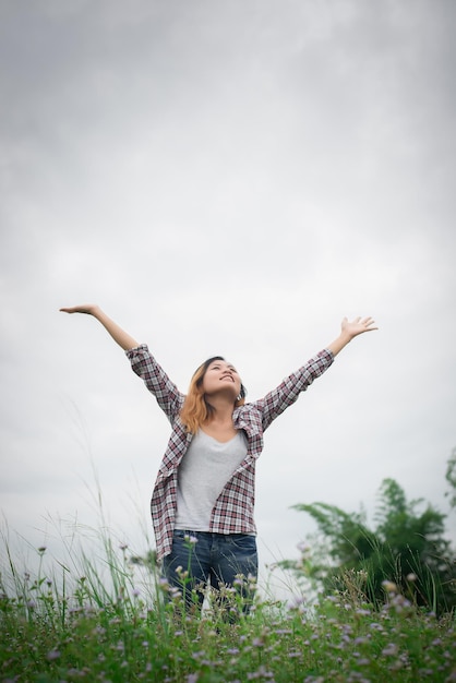 full length of smiling young woman standing on field against sky