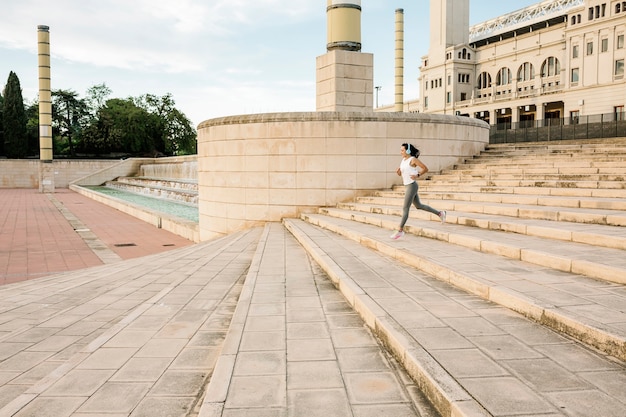 Foto per tutta la lunghezza della donna sportiva che corre all'aperto a montjuic, barcellona