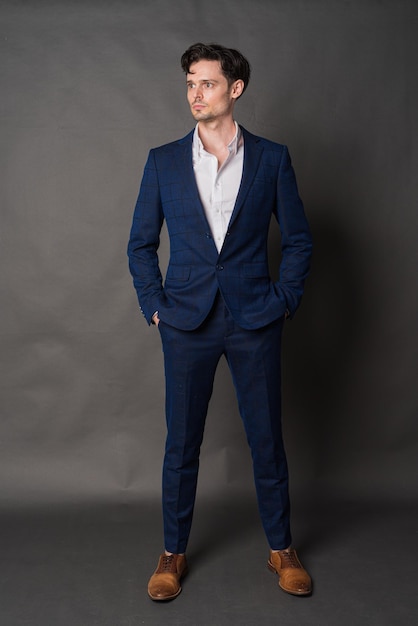 Full length studio portrait of handsome businessman standing against gray background