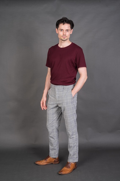 Full length studio portrait of handsome man standing against gray background