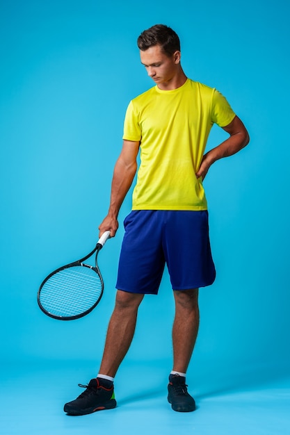 Full length studio portrait of a tennis player man on blue