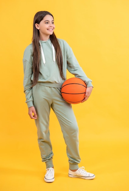 Full length of teen basketball girl isolated on yellow teen basketball girl in studio