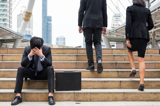 계단 에 동료 들 과 함께 앉아 있는 피곤 한 사업가 의 전체 길이