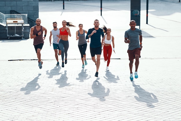 Full length top view of people in sports clothing jogging while exercising on the sidewalk outdoors