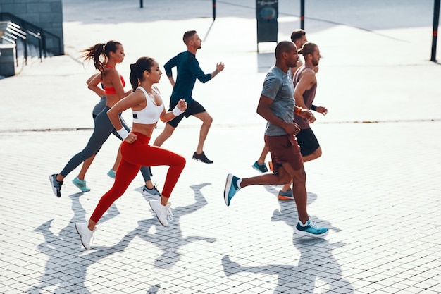 Full length top view of people in sports clothing jogging while exercising on the sidewalk outdoors