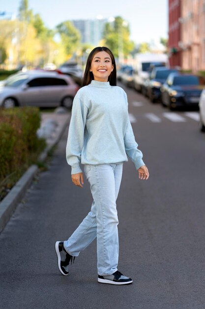 Full length view of cheerful university student feeling happy\
and playful at the street