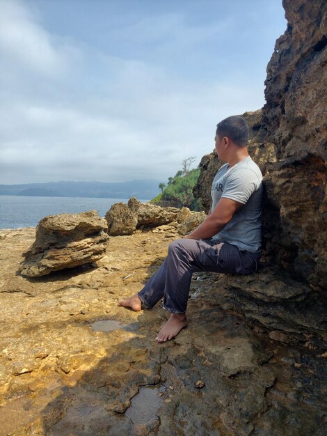 Full length view of an indonesian man sitting on the rock