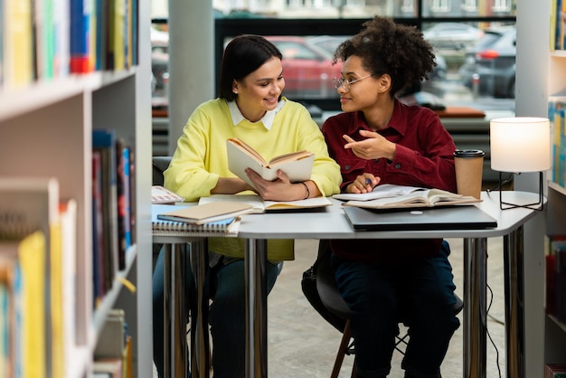 Photo full length view of the two teenage girls enjoying studying together at the library preparing to the exams concept