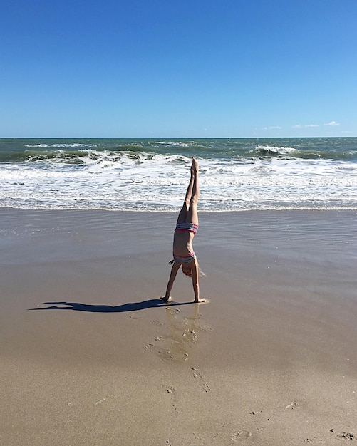 full length of woman on beach against clear sky