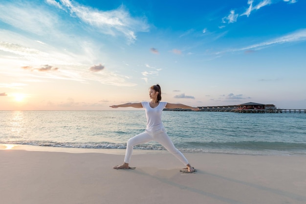 full length of woman exercising at beach during sunrise