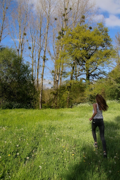 Foto lunghezza completa di donna sull'erba contro gli alberi