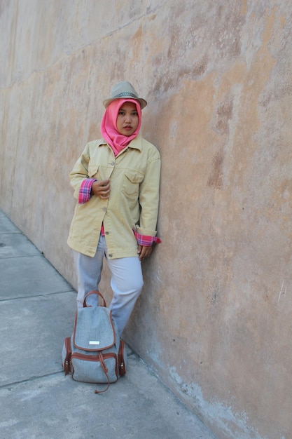 Foto lunghezza completa di una donna con il velo in piedi vicino al muro