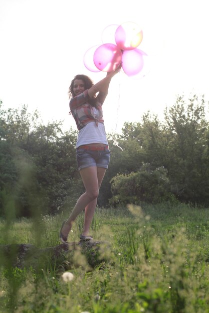 Foto lunghezza completa di donna che tiene i palloncini mentre è in piedi sul campo