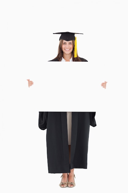 Full length of a woman holding a blank sheet in front of her as she smiles