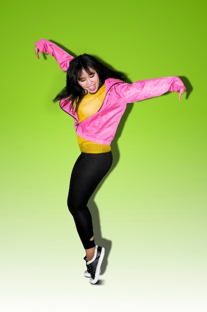 Full length of woman jumping against green background