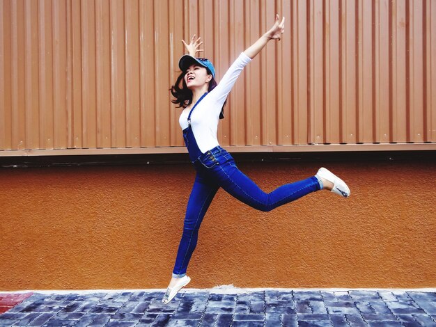 Photo full length of woman jumping against wall