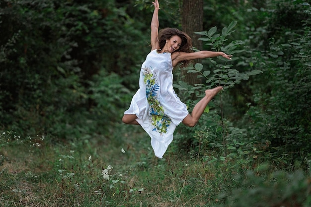 Foto lunghezza completa di una donna che salta nella foresta