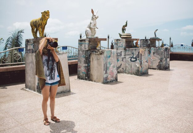 Photo full length of woman photographing while standing against statues