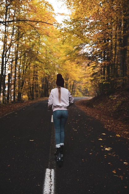 Full length of woman on push scooter in forest during autumn