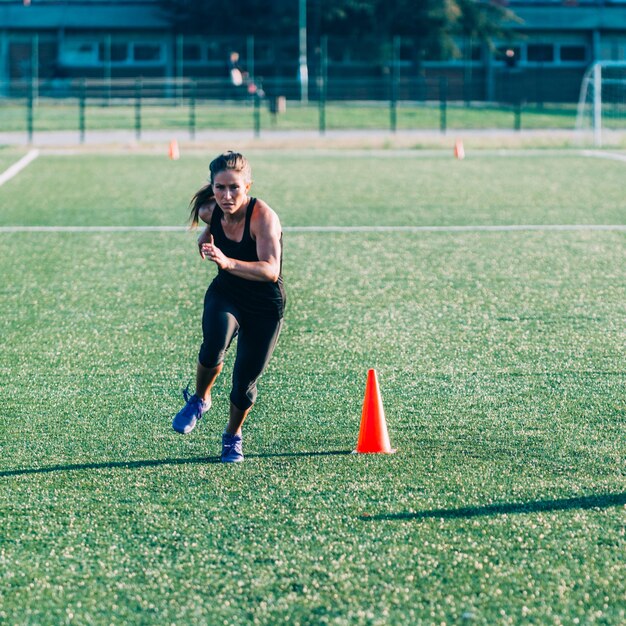 Foto lunghezza completa di una donna che corre sul campo