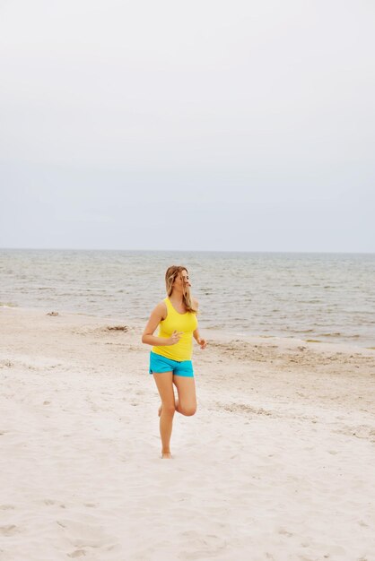 Full length of woman running on shore at beach against sky