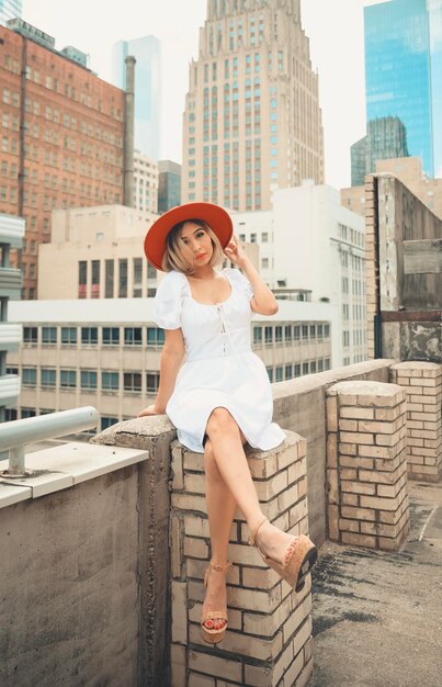 Photo full length of woman sitting against buildings in city