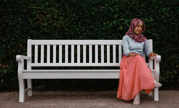 Foto lunghezza completa di una donna seduta su una panchina nel parco