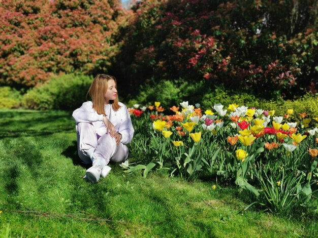 Photo full length of woman sitting by flowers on land