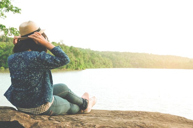 Photo full length of woman sitting on rock by sea