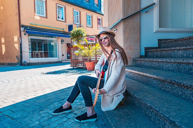 Photo full length of woman sitting on stairs holding guitar