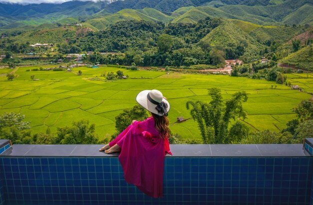 Photo full length of woman sitting on wall against landscape