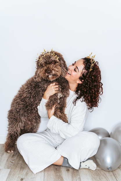 Foto lunghezza completa di donna seduta con il cane contro il muro a casa