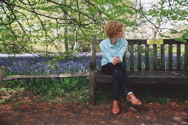 Photo full length of woman sitting on wooden bench against plants at forest