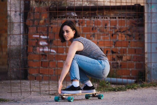 Foto lunghezza completa di una donna che fa skateboard su strada