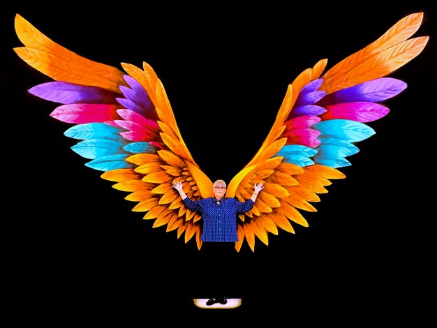 Photo full length of woman standing against colorful wings over black background