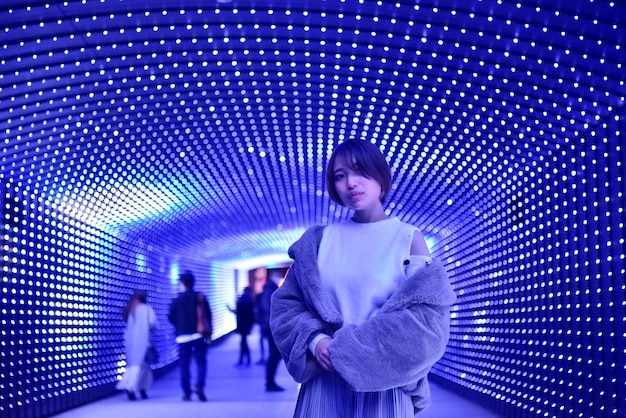 Full length of woman standing against illuminated wall